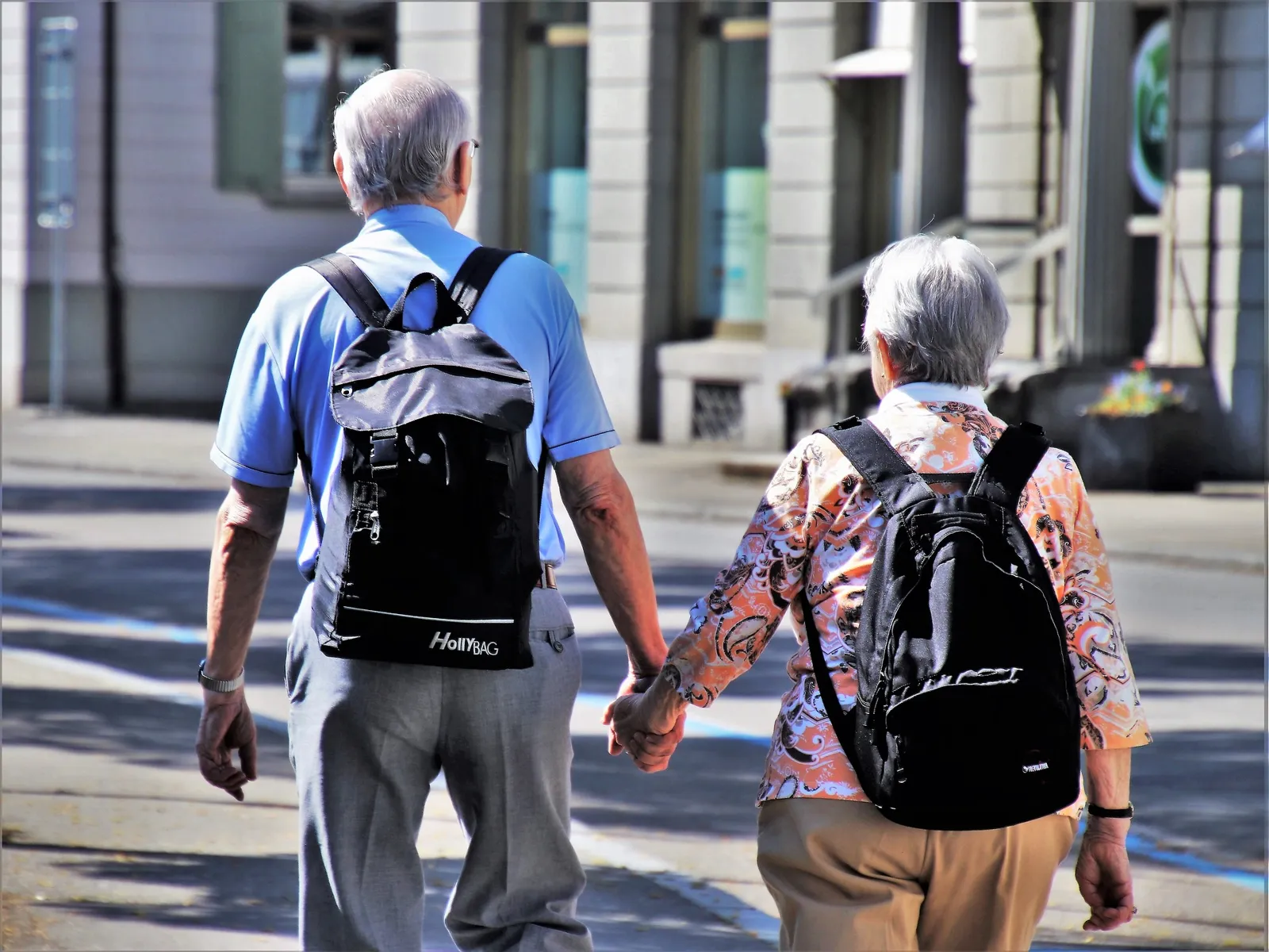 Twee ouderen wandelen hand in hand door de straat