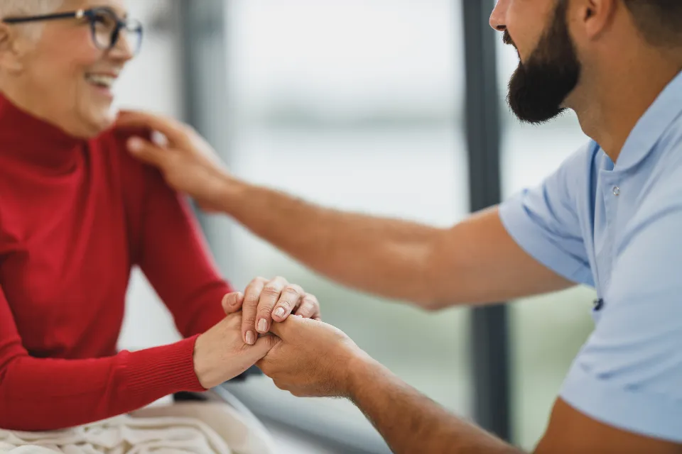 Zorgverlener houdt de handen vast van een oudere vrouw